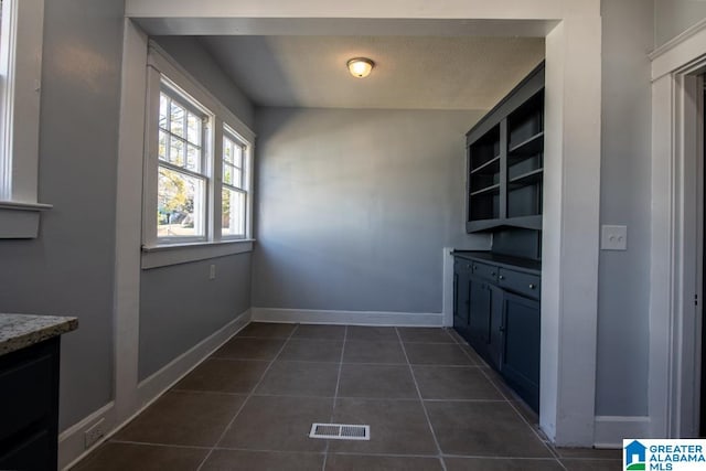 unfurnished dining area featuring dark tile patterned flooring