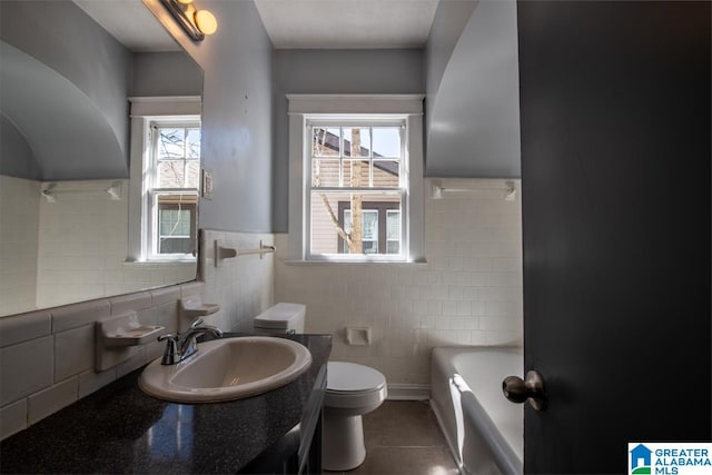 bathroom featuring toilet, tile walls, vanity, and a washtub