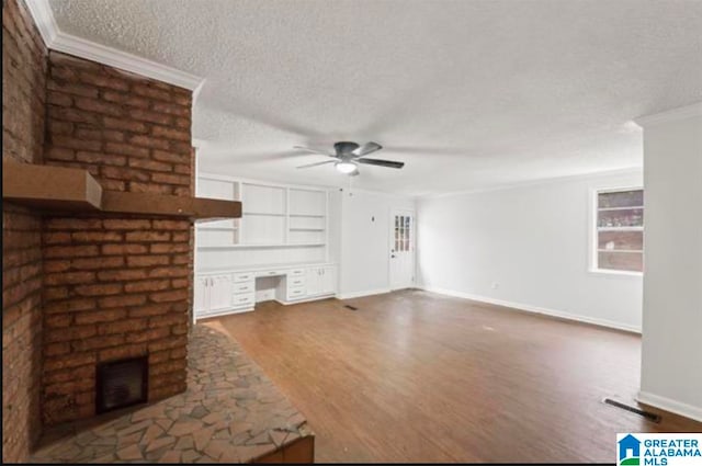 unfurnished living room with dark wood-type flooring, a textured ceiling, ornamental molding, ceiling fan, and built in desk