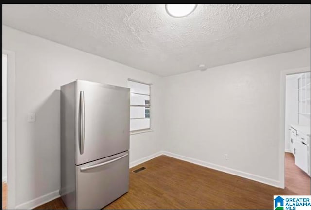 kitchen featuring a textured ceiling, white cabinetry, dark hardwood / wood-style floors, and stainless steel refrigerator