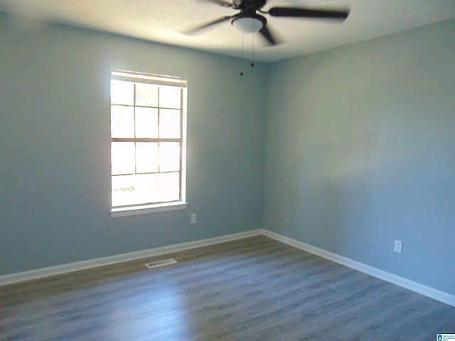 spare room with visible vents, dark wood-type flooring, a textured ceiling, baseboards, and ceiling fan