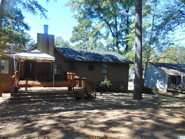 back of house featuring a wooden deck and a chimney