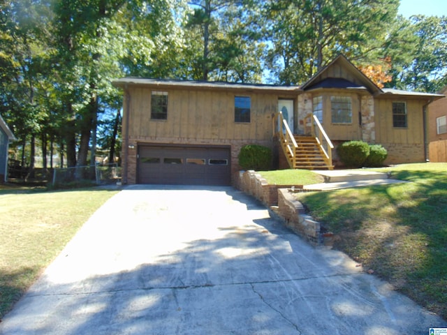 view of front of house featuring a front lawn, concrete driveway, an attached garage, and fence