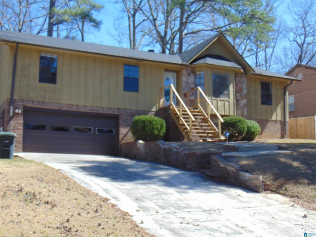 ranch-style home featuring brick siding, an attached garage, stairs, and driveway