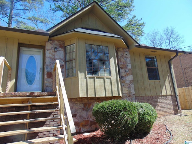 view of exterior entry with board and batten siding and fence