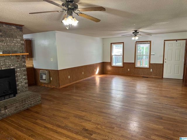 unfurnished living room featuring ceiling fan, a textured ceiling, heating unit, and dark hardwood / wood-style floors