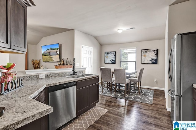 kitchen featuring lofted ceiling, sink, dark brown cabinetry, appliances with stainless steel finishes, and dark hardwood / wood-style flooring