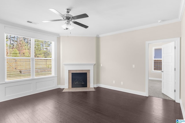 unfurnished living room with ornamental molding, a tiled fireplace, dark hardwood / wood-style floors, and ceiling fan