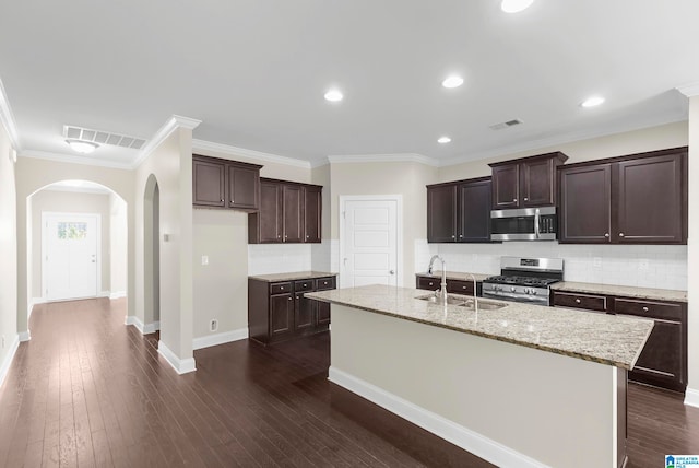 kitchen featuring a center island with sink, appliances with stainless steel finishes, dark hardwood / wood-style floors, ornamental molding, and sink