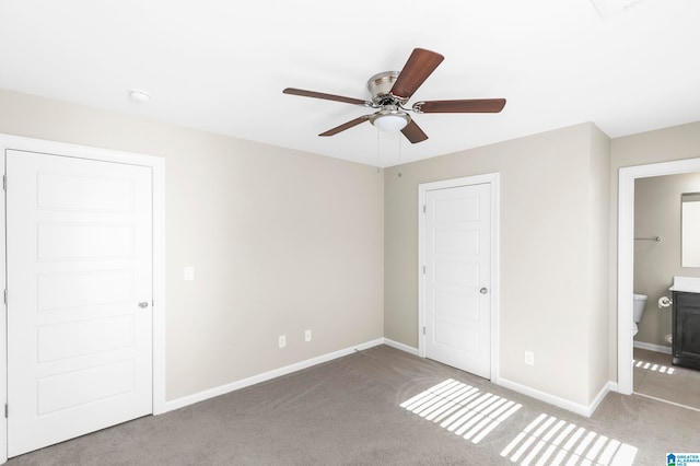 unfurnished bedroom featuring ensuite bath, light colored carpet, and ceiling fan