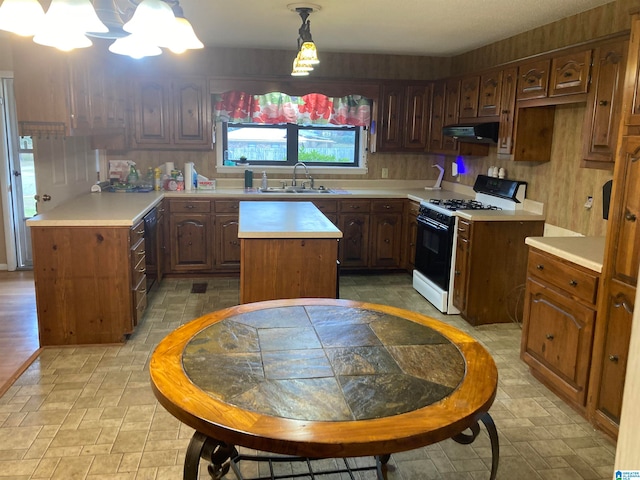 kitchen with decorative backsplash, white gas range oven, sink, a center island, and pendant lighting