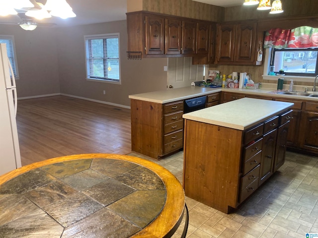 kitchen with a chandelier, light wood-type flooring, sink, dark brown cabinetry, and a center island