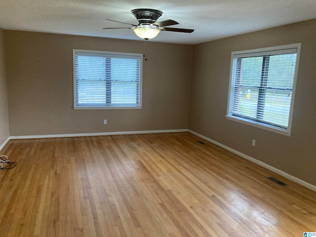 empty room featuring light hardwood / wood-style flooring, a textured ceiling, and ceiling fan