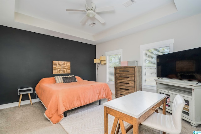 bedroom featuring ceiling fan, a raised ceiling, and light carpet