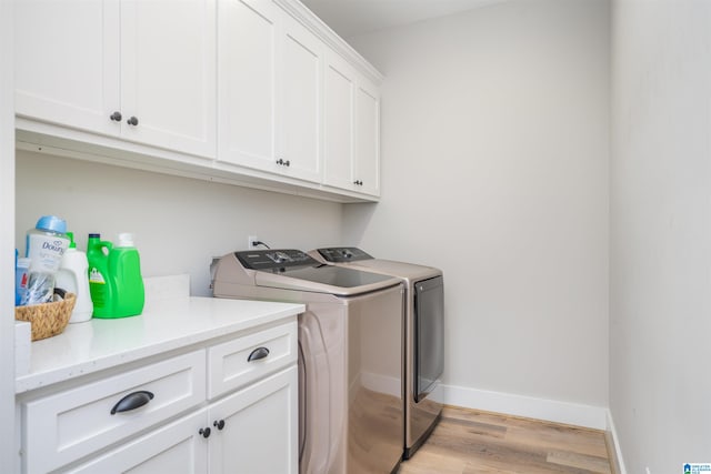 laundry room with light hardwood / wood-style floors, cabinets, and washing machine and clothes dryer