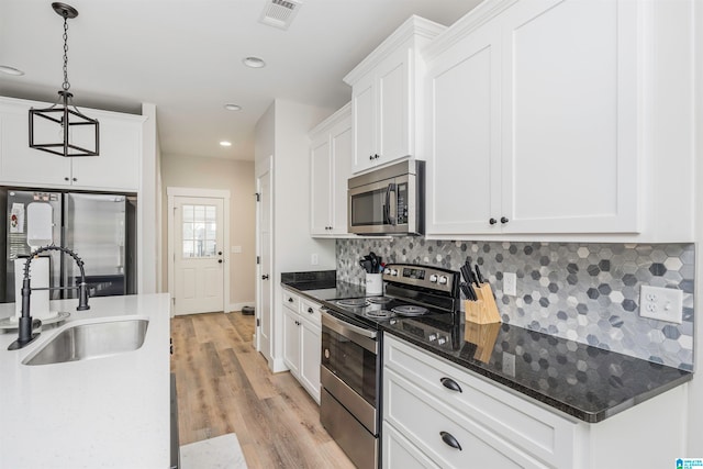 kitchen featuring stainless steel appliances, sink, decorative light fixtures, white cabinets, and light hardwood / wood-style floors