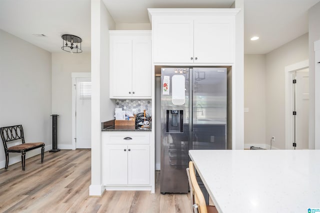 kitchen with light hardwood / wood-style floors, white cabinets, tasteful backsplash, and stainless steel fridge with ice dispenser