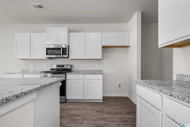 kitchen featuring light stone countertops, stainless steel appliances, and white cabinetry