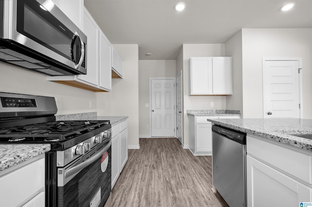 kitchen featuring light hardwood / wood-style floors, light stone counters, white cabinetry, and stainless steel appliances