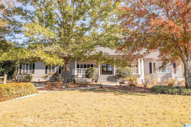 view of property hidden behind natural elements with covered porch and a front yard