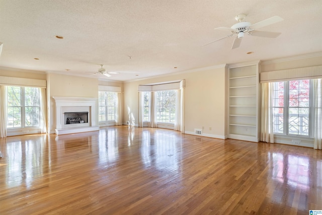 unfurnished living room featuring ornamental molding, ceiling fan, light hardwood / wood-style floors, and plenty of natural light