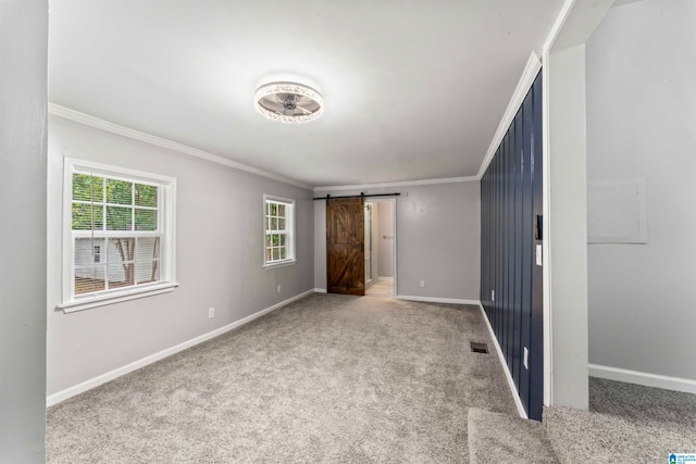 unfurnished bedroom with a barn door, ornamental molding, and carpet floors