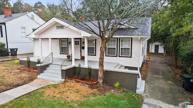 bungalow featuring a porch and a storage unit