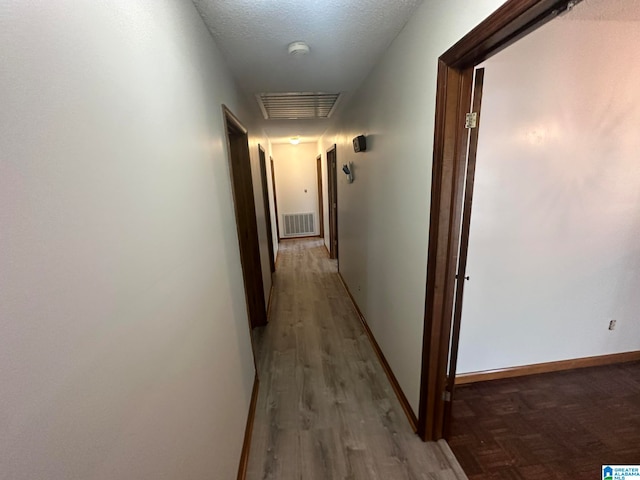 hall with a textured ceiling and hardwood / wood-style flooring