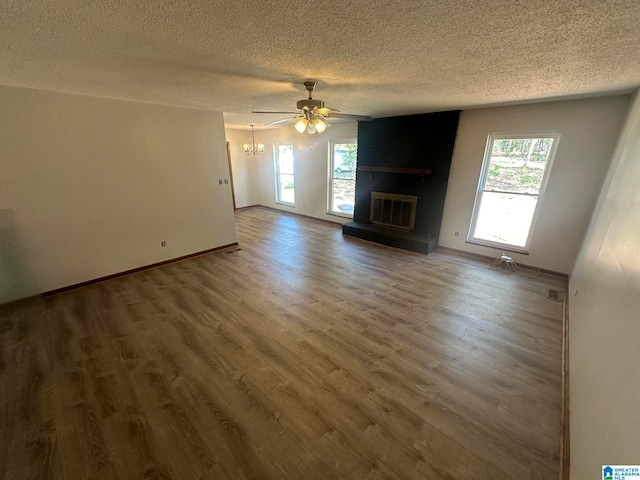 unfurnished living room with a fireplace, ceiling fan, plenty of natural light, and dark hardwood / wood-style floors