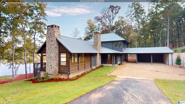 view of front of property featuring a front lawn, a carport, and a water view