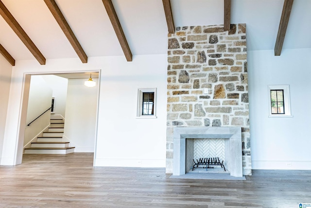 unfurnished living room featuring high vaulted ceiling, beamed ceiling, hardwood / wood-style floors, and a fireplace