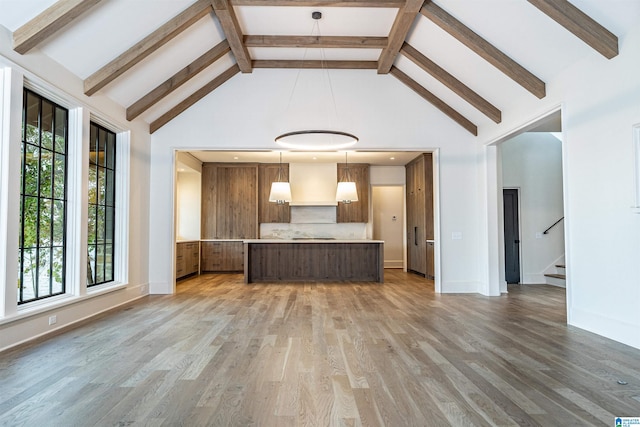 kitchen with hanging light fixtures, hardwood / wood-style flooring, beamed ceiling, and high vaulted ceiling