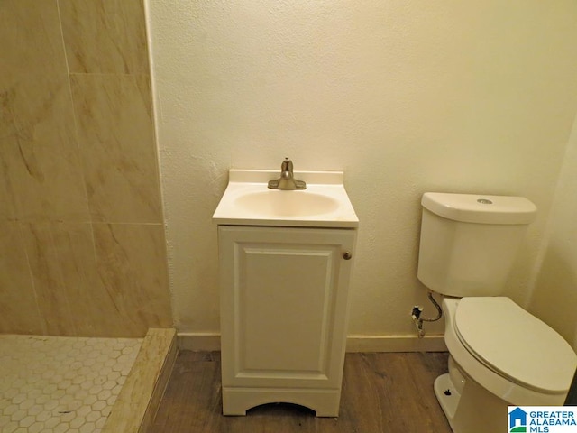 bathroom with hardwood / wood-style floors, vanity, toilet, and walk in shower