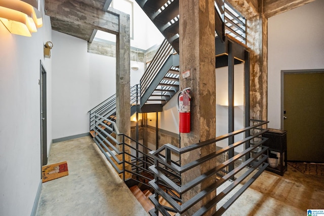 stairs featuring concrete floors and a high ceiling