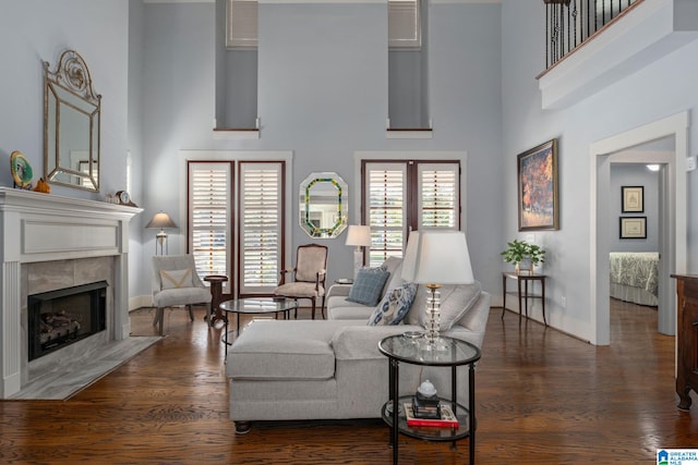 living room with a tiled fireplace, a high ceiling, and dark hardwood / wood-style flooring