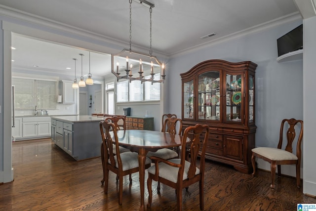 dining area with sink, ornamental molding, dark hardwood / wood-style flooring, and an inviting chandelier