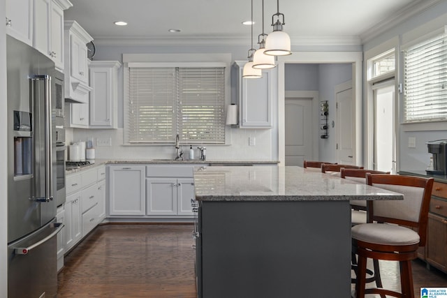 kitchen featuring a breakfast bar area, a kitchen island, white cabinetry, sink, and stainless steel appliances