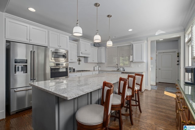 kitchen featuring white cabinets, stainless steel appliances, a wealth of natural light, and hanging light fixtures