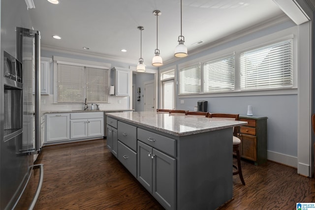 kitchen featuring dark hardwood / wood-style flooring, a kitchen island, a breakfast bar, white cabinetry, and pendant lighting