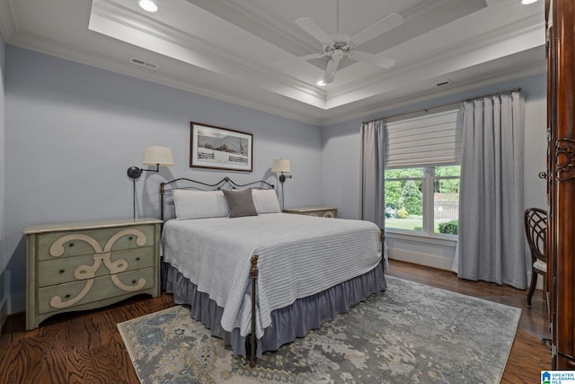 bedroom featuring crown molding, dark hardwood / wood-style floors, ceiling fan, and a raised ceiling