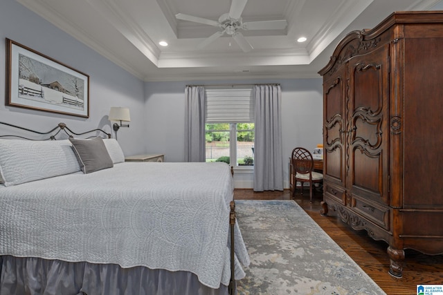 bedroom featuring ornamental molding, dark hardwood / wood-style floors, a tray ceiling, and ceiling fan