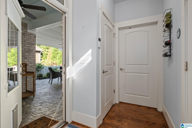 doorway with dark wood-type flooring and ceiling fan