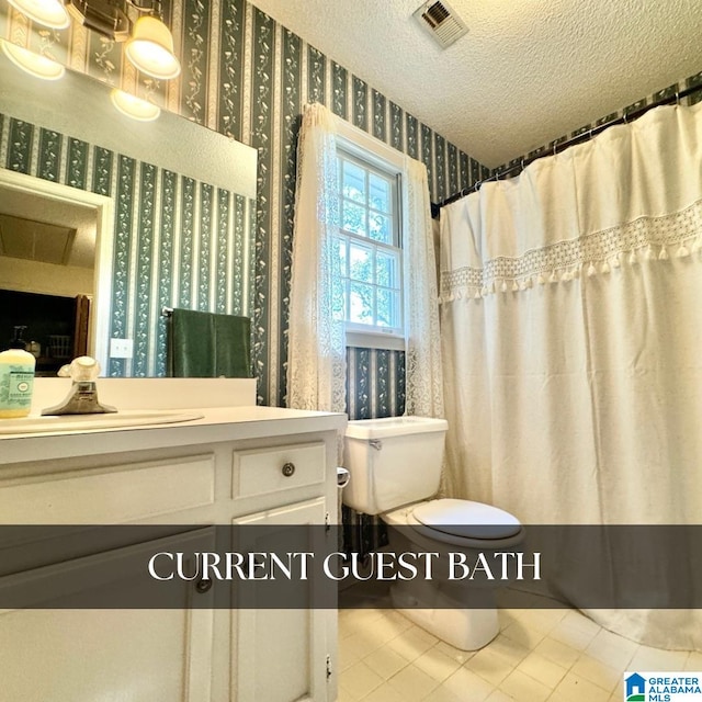 bathroom with vanity, toilet, a textured ceiling, and tile patterned flooring