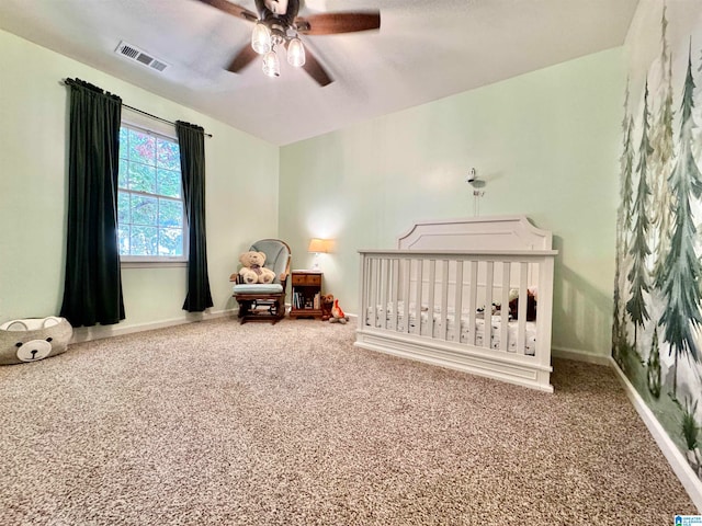 carpeted bedroom featuring a crib and ceiling fan