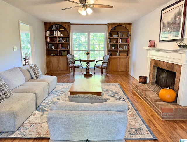 living room with a textured ceiling, plenty of natural light, a fireplace, and hardwood / wood-style floors