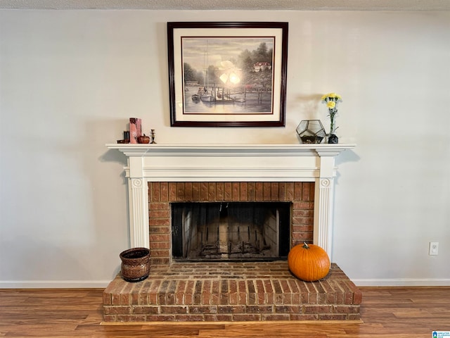 interior details with hardwood / wood-style floors, a textured ceiling, and a brick fireplace