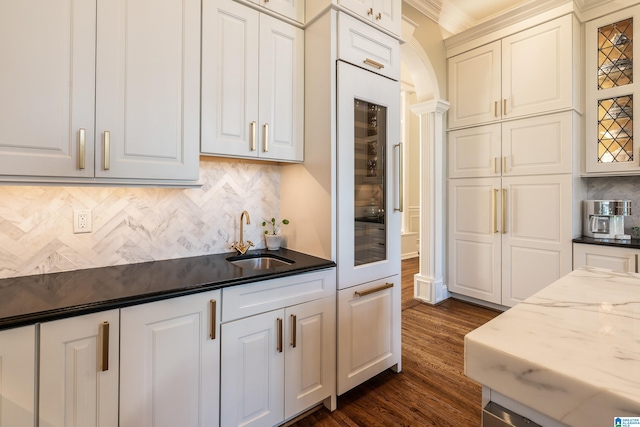 kitchen featuring decorative backsplash, white cabinets, dark stone counters, dark hardwood / wood-style floors, and sink