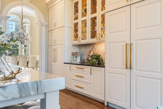 bar with decorative backsplash, ornate columns, dark hardwood / wood-style floors, crown molding, and white cabinets