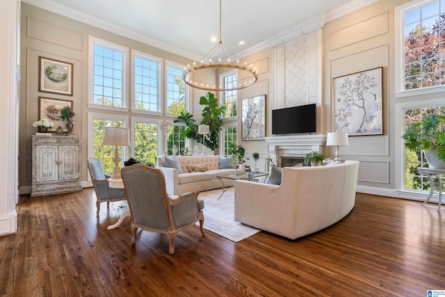 living room featuring ornamental molding, a high ceiling, hardwood / wood-style flooring, and an inviting chandelier