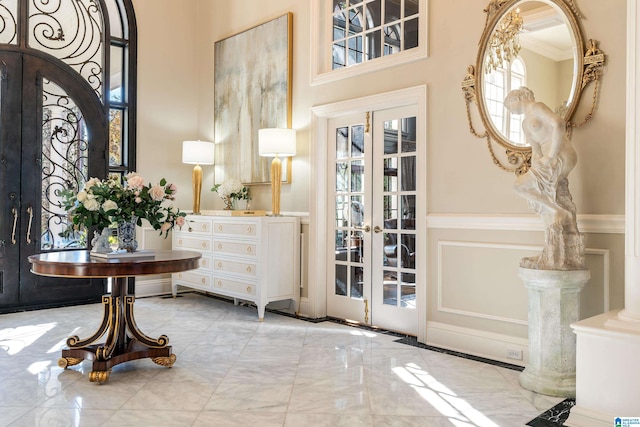 entrance foyer featuring french doors, ornamental molding, and a high ceiling